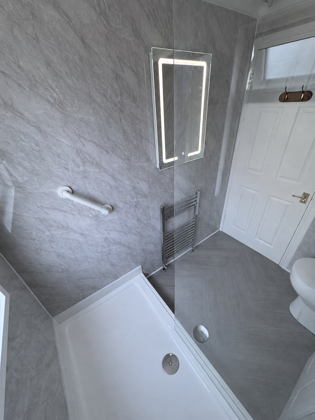 Illuminated mirror and radiator fitted over bathroom wall panels